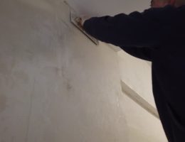 Un plâtrier travaille sur la finition des murs et des plafonds. En effet, il applique du plâtre pour obtenir des surfaces lisses