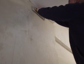 Un plâtrier travaille sur la finition des murs et des plafonds. En effet, il applique du plâtre pour obtenir des surfaces lisses